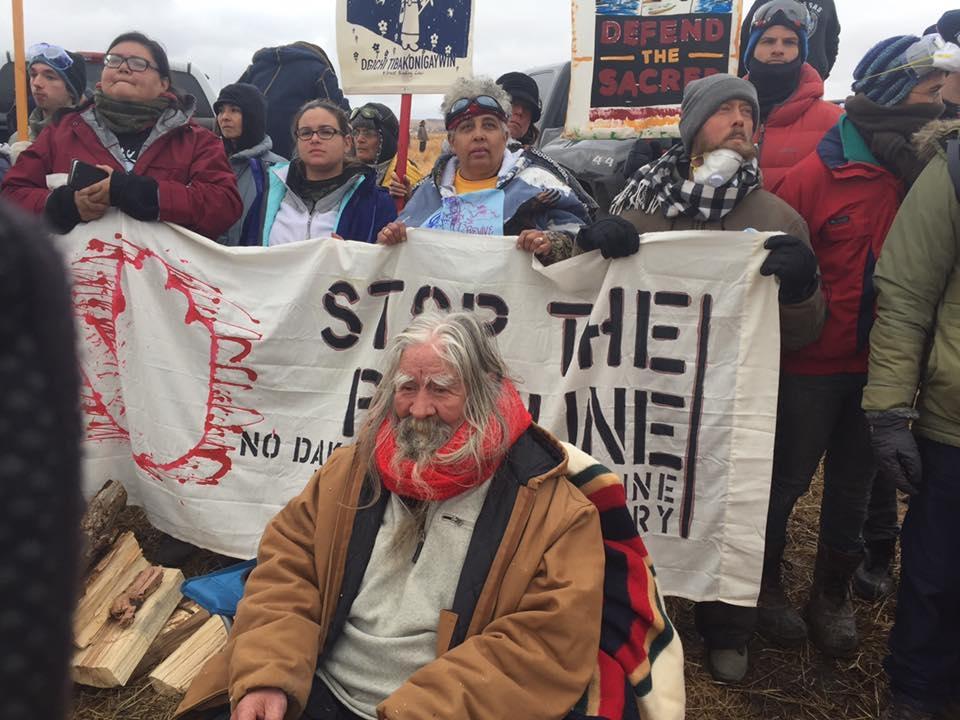 Water Protectors holding up a sign that says 