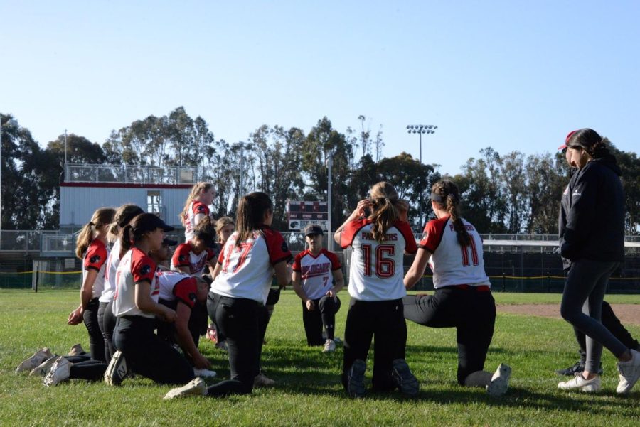 The girls’ varsity team huddled after their game in the outfield and chatted with coaches.