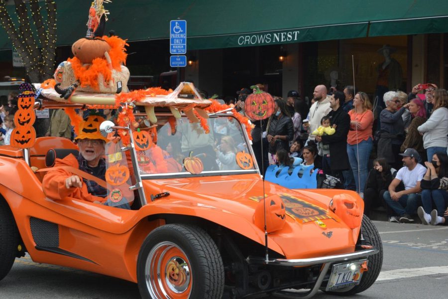 Showing their pumpkin spirit, Half Moon Bay locals wear festive costumes while driving in a decorated car during the Great Pumpkin Parade.