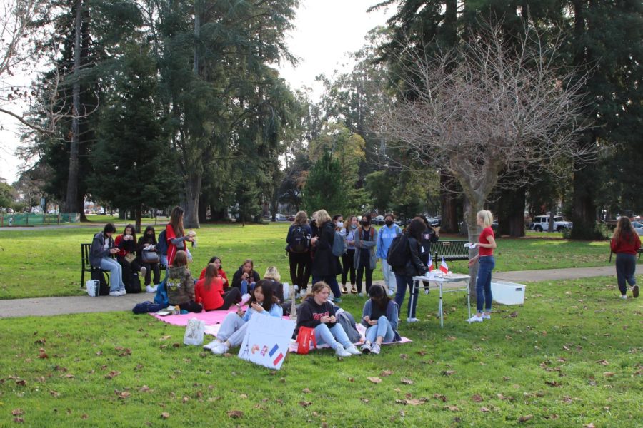 Students gather in the front lawn during lunch for a picnic with French pastries, including chocolate eclairs.