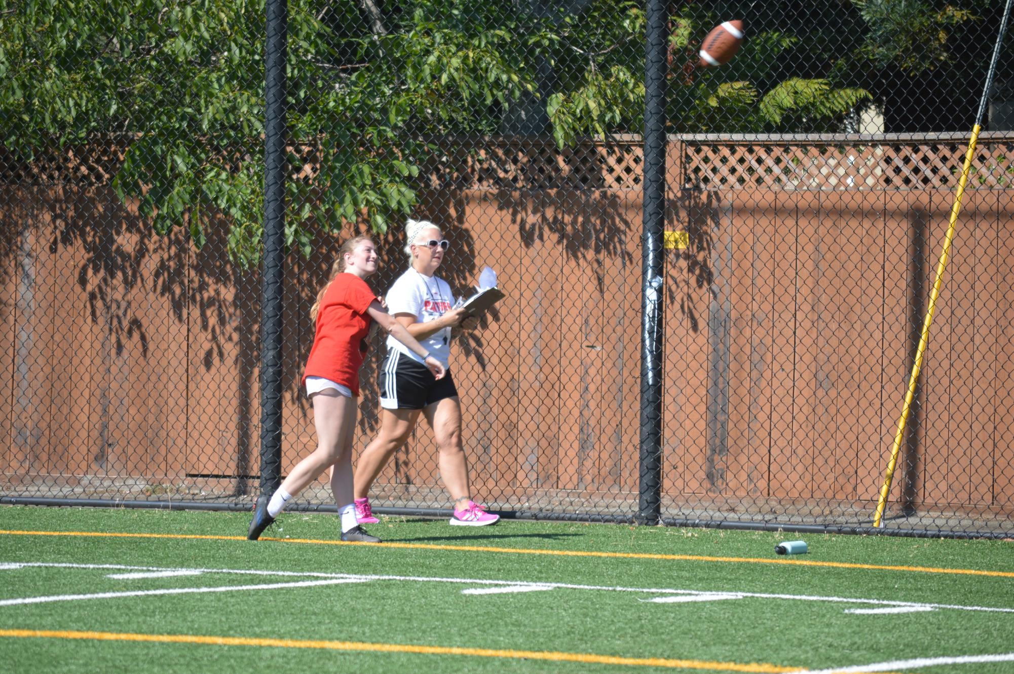 Sophomore Brooke Schuman is watched by coach Denise Burch as she throws a strong spiral to her partner during the intense tryouts.