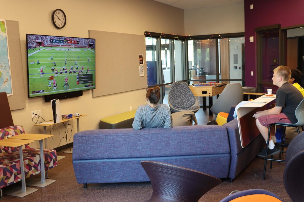 Younger+students+and+a+Recreation+Center+coordinator+watch+a+football+game+in+the+new+teen+space%2C+which+offers+a+TV%2C+video+games+and+relaxing+seating.