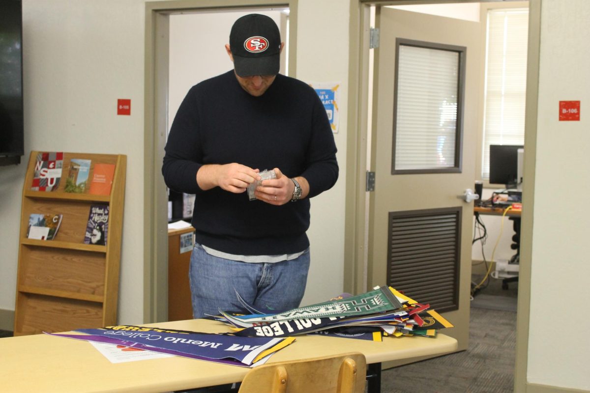 College and Career Advisor Jonathan Dhyne sets up college banners to decorate his new office space.