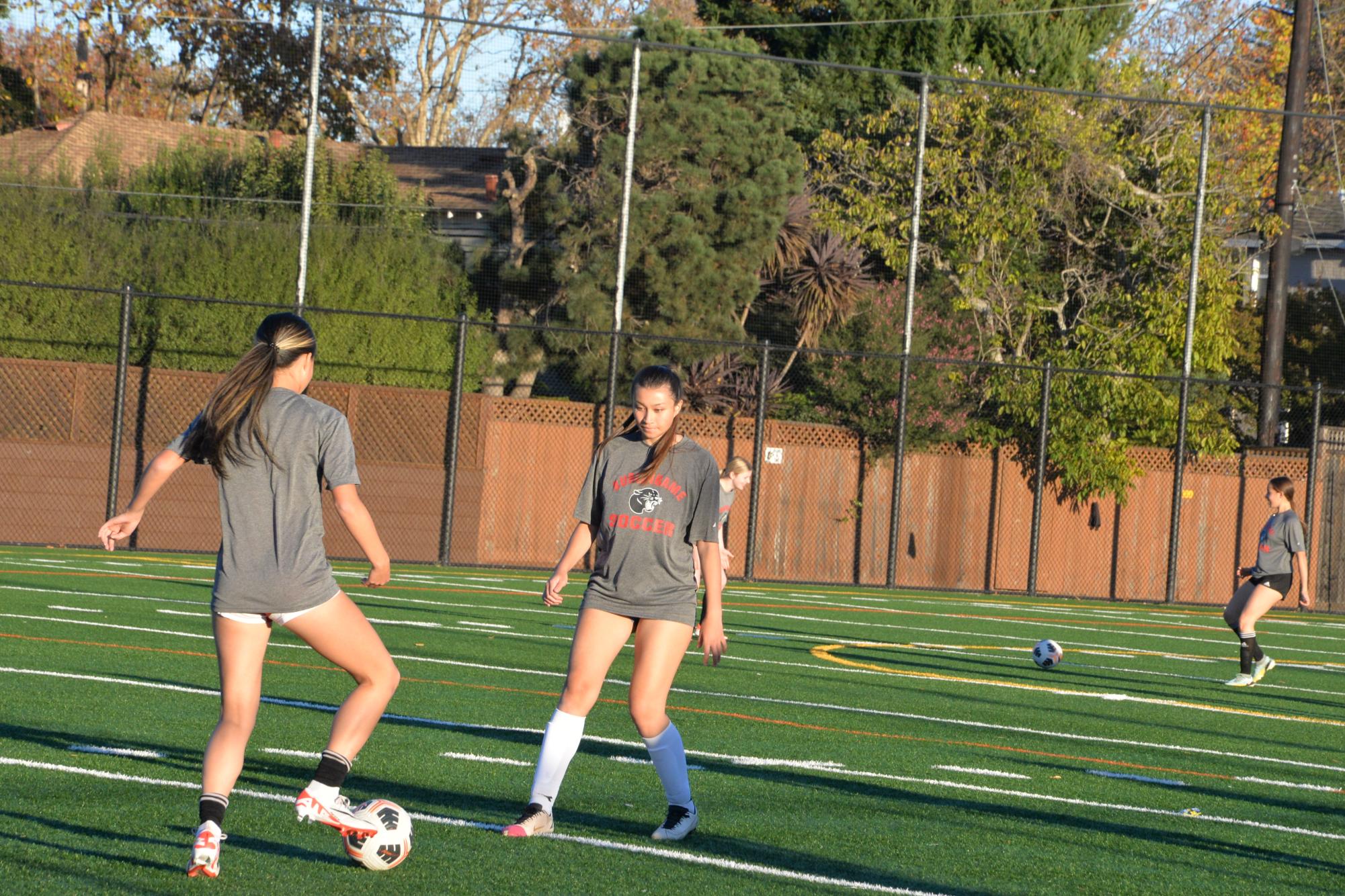 Seniors Olivia Armstrong and Kaylee Ng pass the ball to each other during practice.