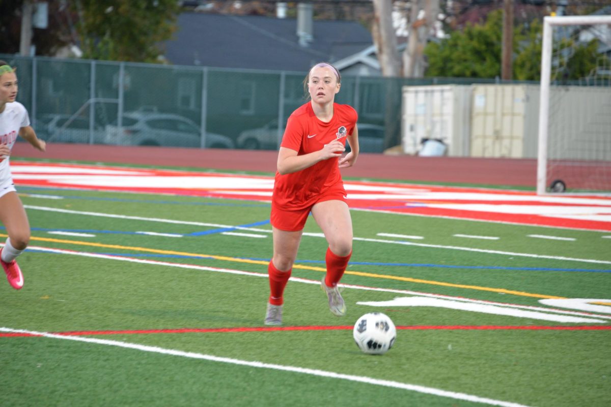 Junior Emma Daly searches for a player to pass the ball to as she dribbles past a forward from Redwood High School.