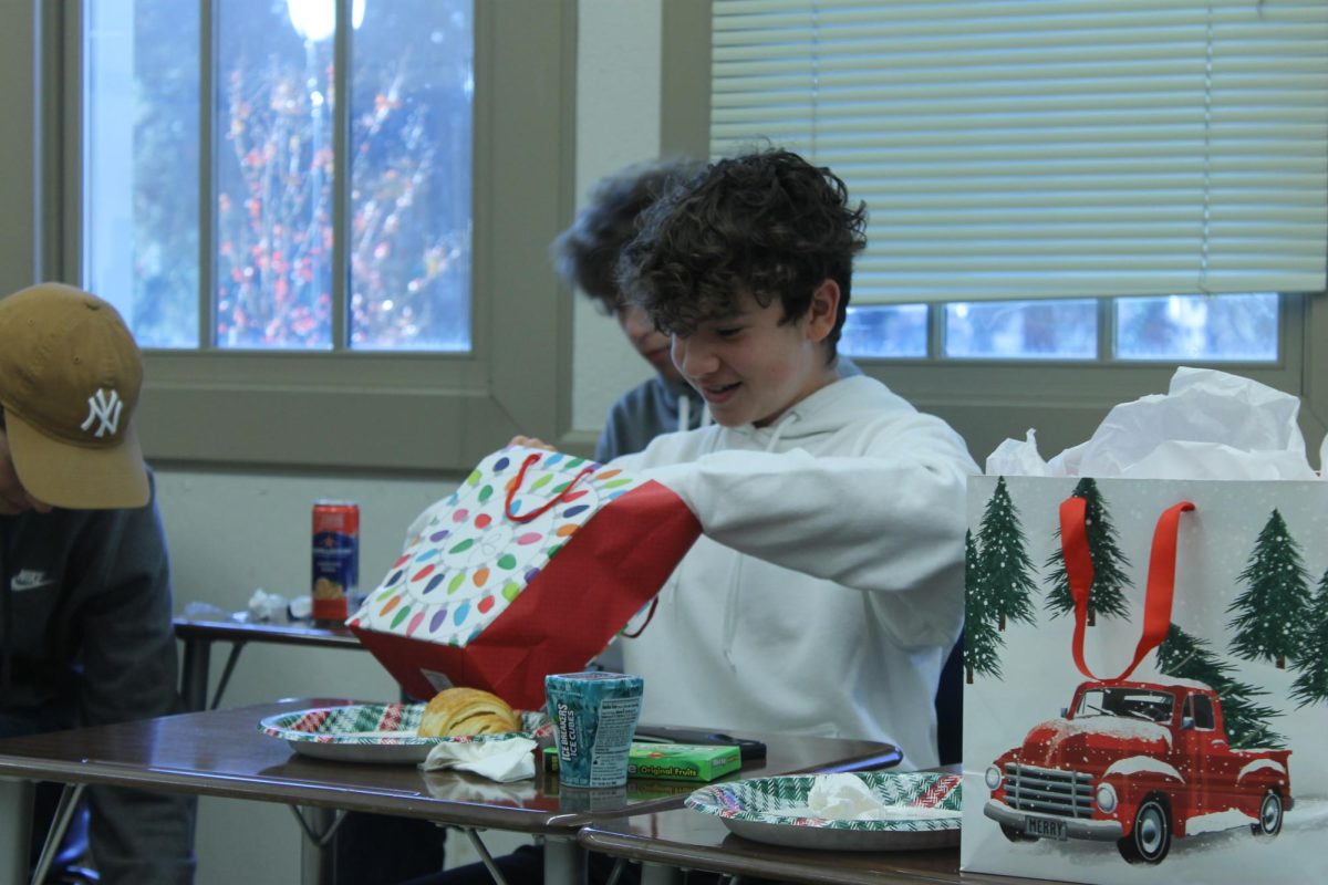 Sophomore Henry Gardner eagerly opens his present during the journalism class’ yearly Secret Santa exchange.