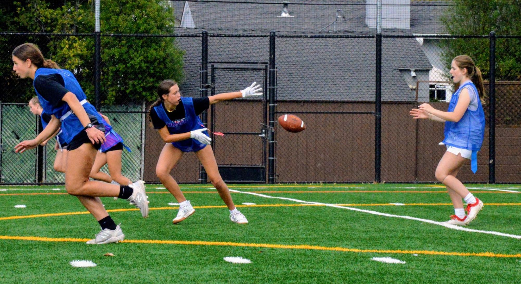 During a scrimmage on Aug. 23, senior and center Naomi Leslie snaps the ball to senior and quarterback Miranda Sibley while the rest of the team charges on the offense. 