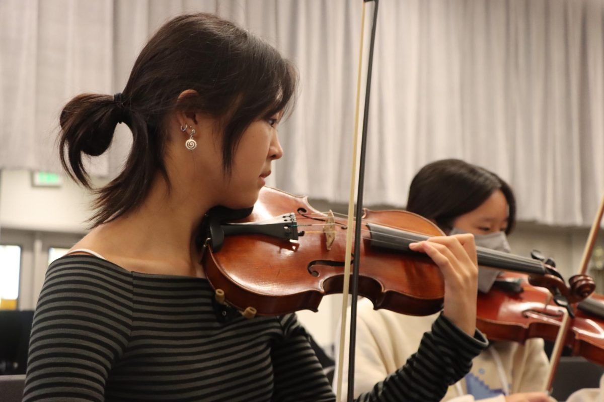 Strings president and sophomore Sophia Chang sight reads her music as they practice in preparation for back-to-school night. 