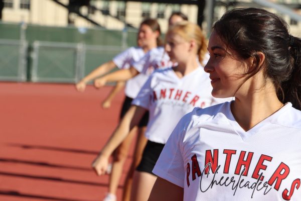 Junior Mia Robelo ends the half-time routine with a smile as the cheer squad practices in preparation for the upcoming away game. 