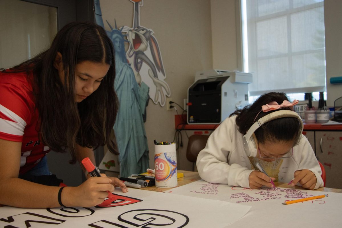 Bay Academy senior Hailey Han and leadership student and senior Mayu Simpson make posters together for the first flag football game on Wednesday, Sept. 4.