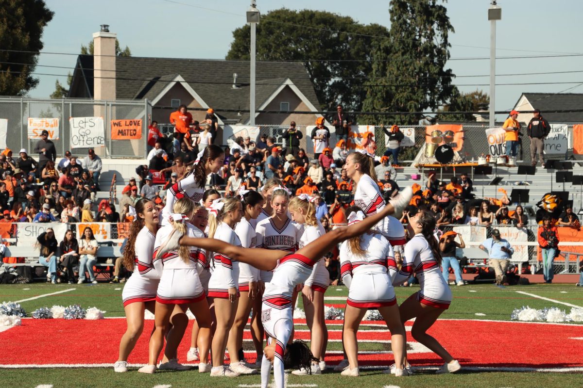 Tumblers perform flips as the rest of the team prepares for their pyramid stunt.