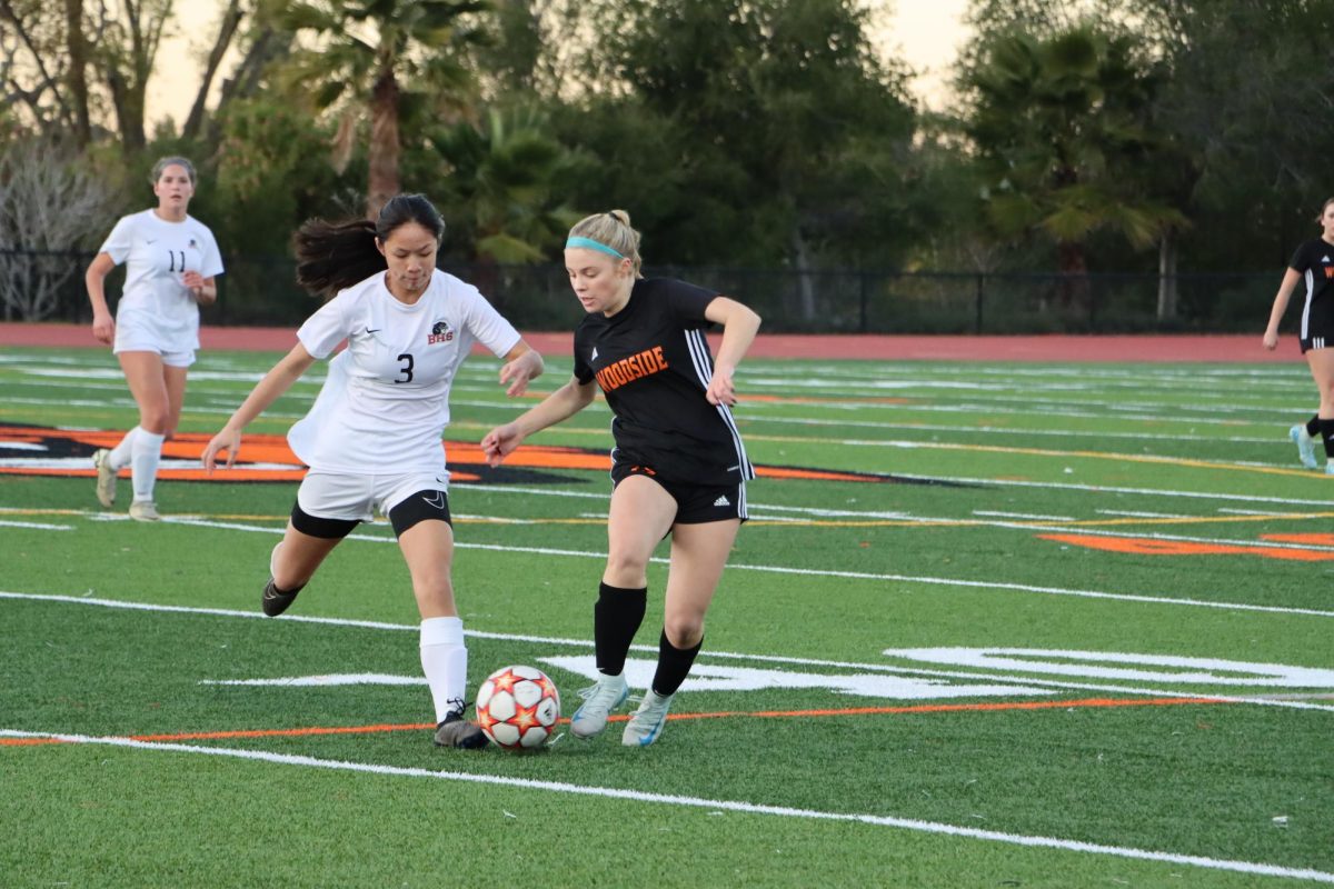 Sophomore Lauren Dener narrowly beats the Woodside defender and prepares to pass.