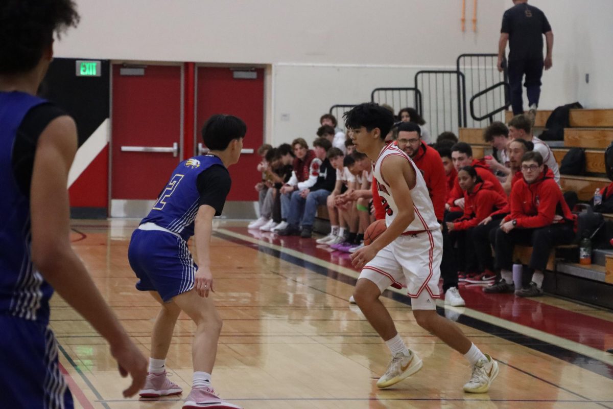 Junior point guard Jean-Luc Uharriet tries to get past an Oak Grove defender.