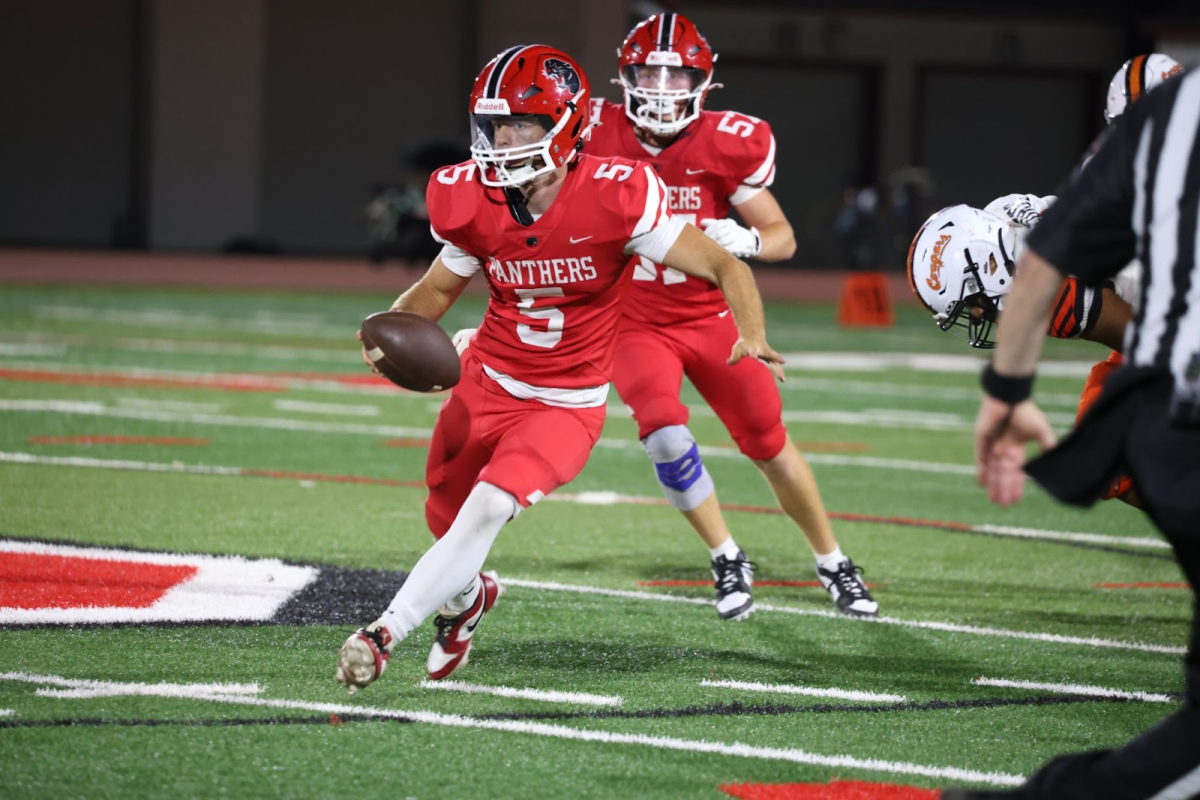 Senior quarterback Nick Armstrong scrambles up the field with the ball, avoiding defenders.