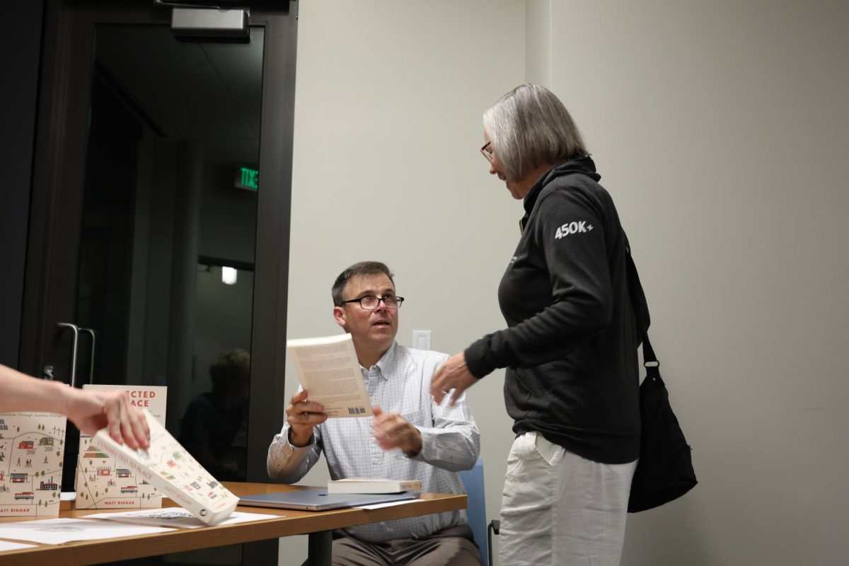 Community member receives a signed book, “Connected to Place,” after Biggar’s presentation and panel.