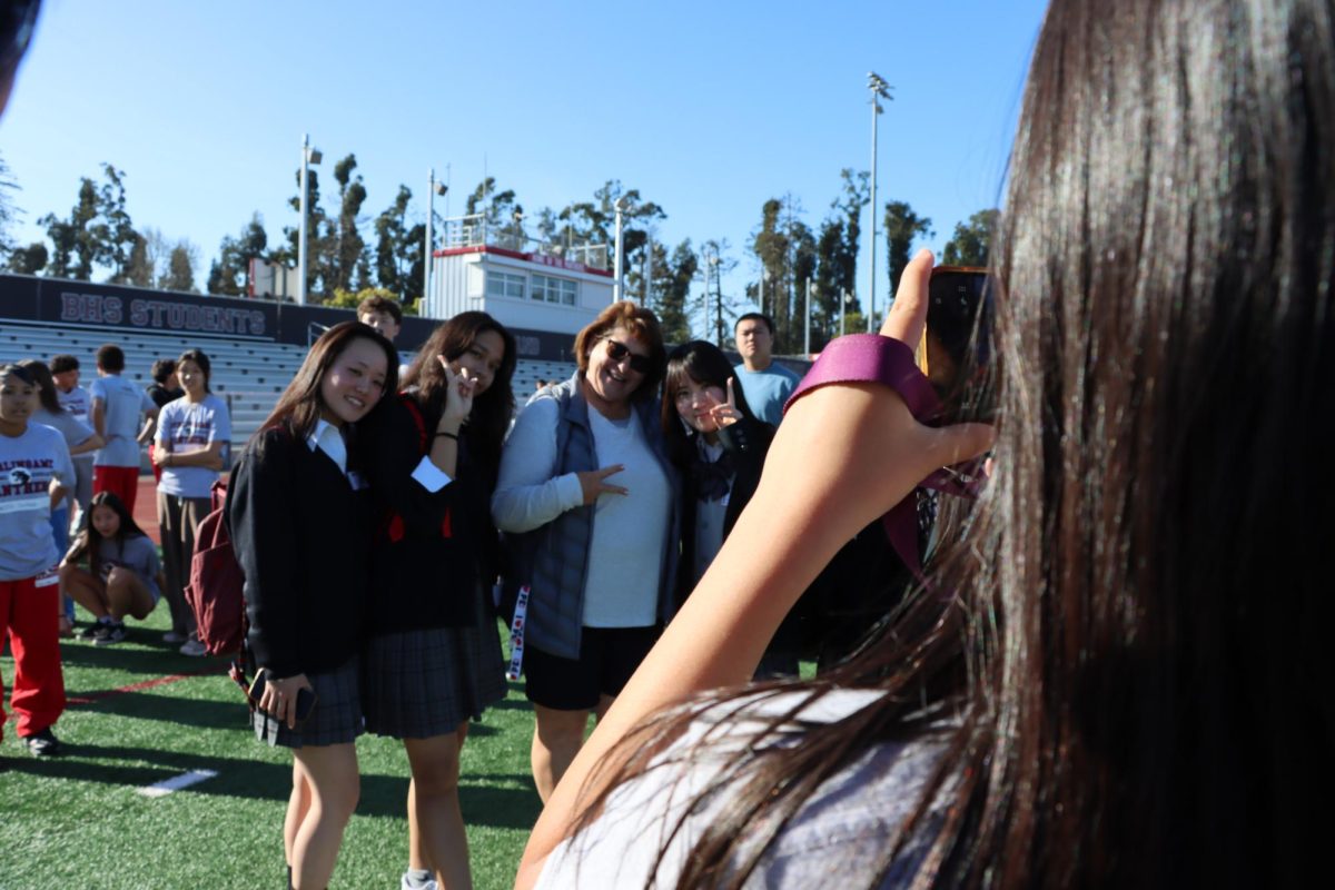 Physical education teacher Laurie Hudelson takes a photo with Japanese exchange students.